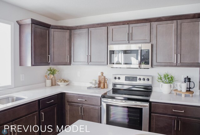 kitchen with light countertops, dark brown cabinetry, stainless steel appliances, and a sink
