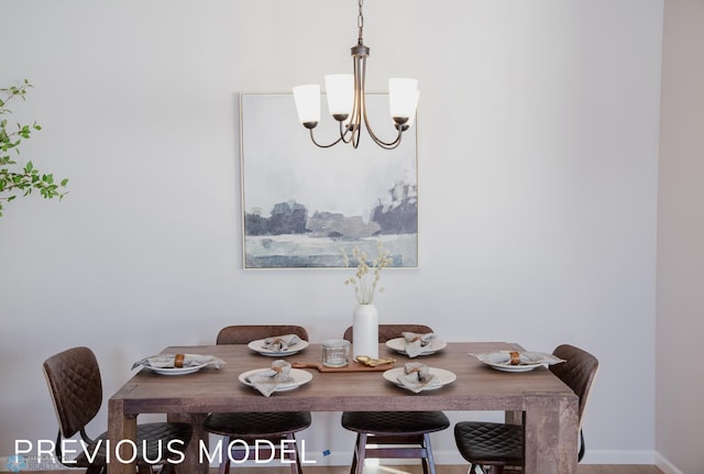 dining room with baseboards, wood finished floors, and a notable chandelier