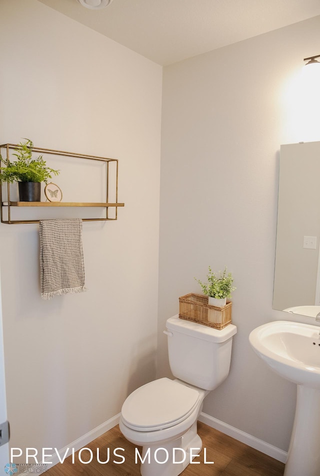 bathroom featuring baseboards, wood finished floors, and toilet