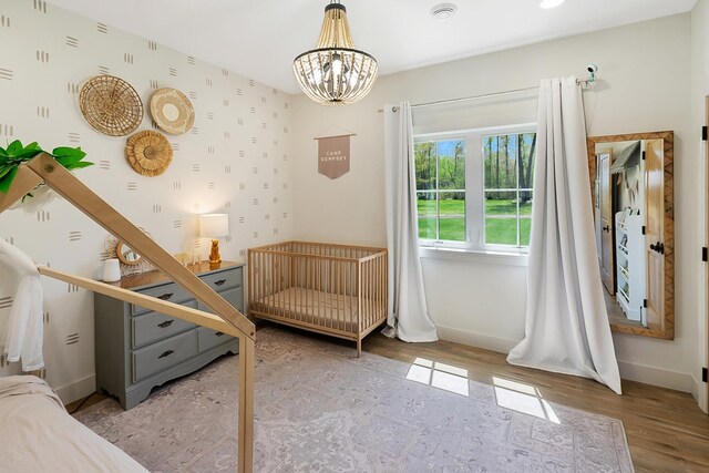 38525 Northstar Dr, Cushing, MN 56443 - unfurnished bedroom featuring a chandelier, baseboards, wood finished floors, and wallpapered walls