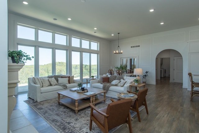 38525 Northstar Dr, Cushing, MN 56443 - living area featuring visible vents, a chandelier, a towering ceiling, arched walkways, and a decorative wall