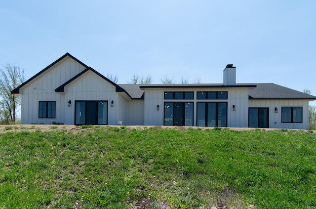 38525 Northstar Dr, Cushing, MN 56443 - rear view of house featuring board and batten siding, a chimney, and a yard