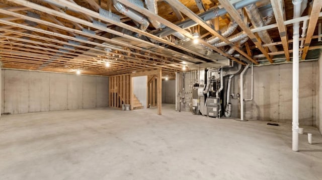 unfinished below grade area featuring heating unit and stairs