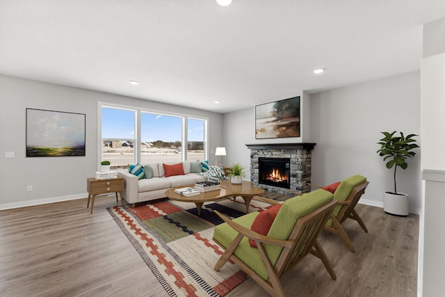 living room featuring baseboards, recessed lighting, wood finished floors, and a fireplace