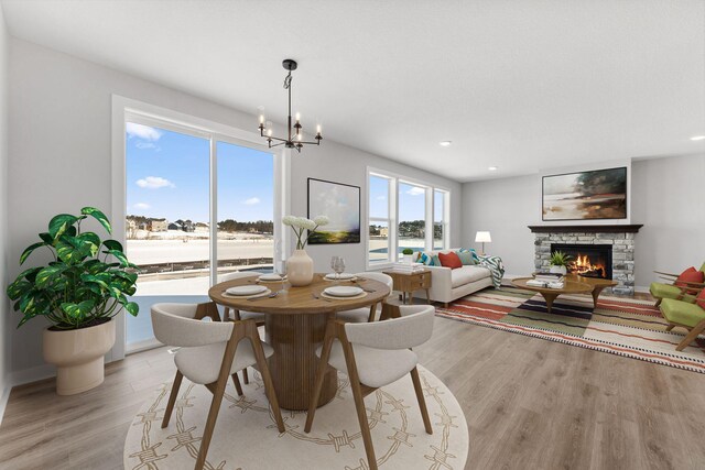 dining area with recessed lighting, a notable chandelier, light wood-style flooring, and a fireplace