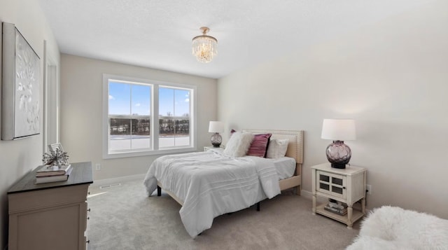 carpeted bedroom with baseboards, an inviting chandelier, and visible vents