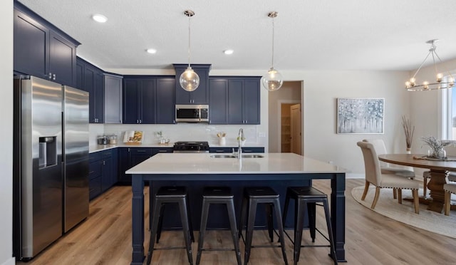 kitchen with a sink, light countertops, a breakfast bar area, stainless steel appliances, and blue cabinets
