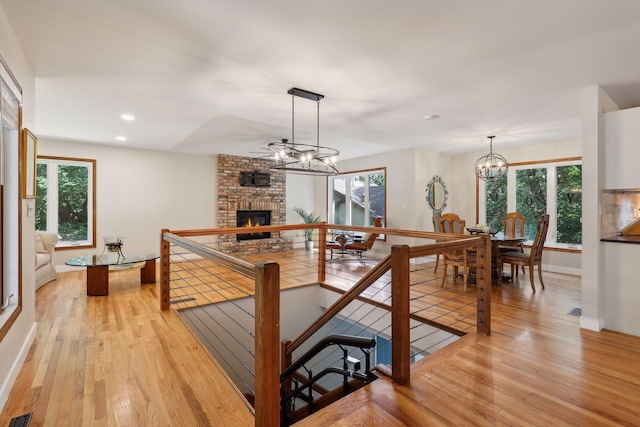 17180 Jordan Ct, Lakeville, MN 55044 - kitchen with a brick fireplace, light wood finished floors, a chandelier, baseboards, and hanging light fixtures