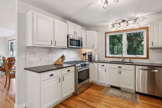 17180 Jordan Ct, Lakeville, MN 55044 - kitchen with stainless steel appliances, a sink, light wood finished floors, and dark countertops