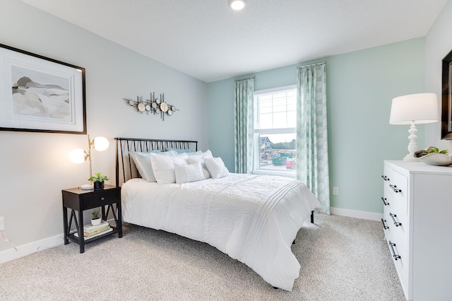 bedroom with light colored carpet and baseboards