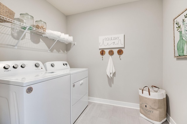 clothes washing area with separate washer and dryer and baseboards