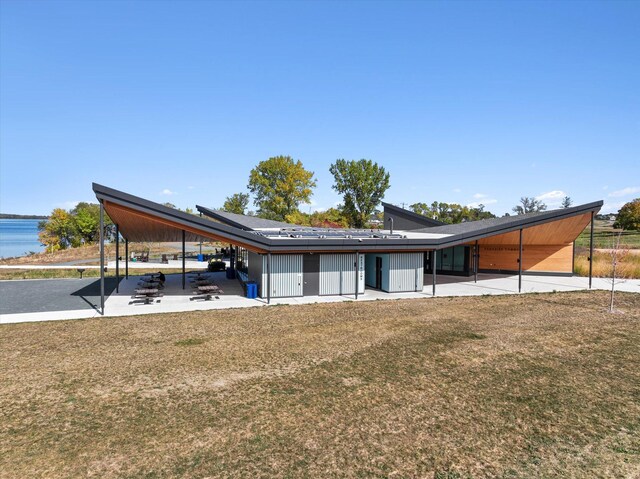 view of front facade with a front yard, a patio, and a water view