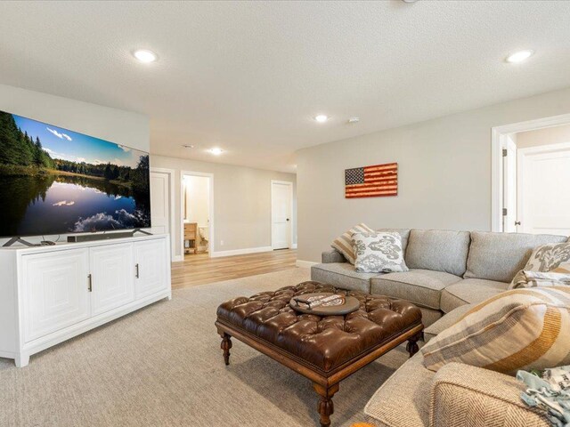 living area with recessed lighting, light carpet, and baseboards