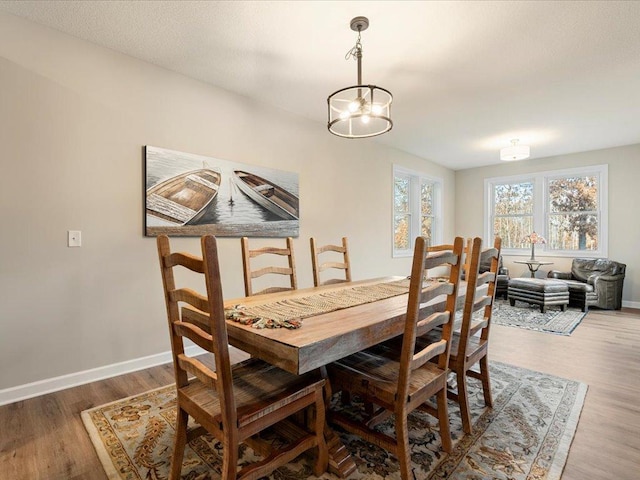 dining space featuring wood finished floors, baseboards, and a chandelier