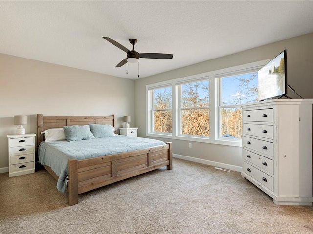 bedroom featuring light colored carpet, baseboards, and ceiling fan
