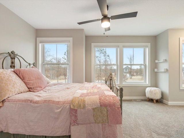 carpeted bedroom with baseboards, multiple windows, and a ceiling fan