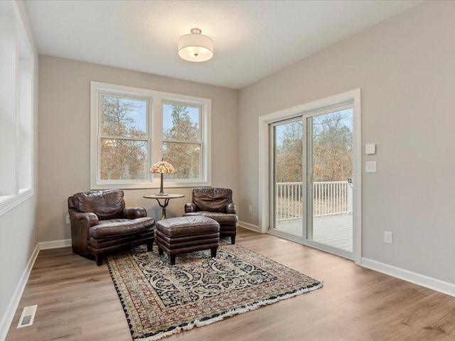 living area with light wood-style flooring, plenty of natural light, and baseboards