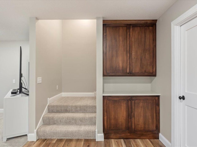 staircase featuring wood finished floors and baseboards