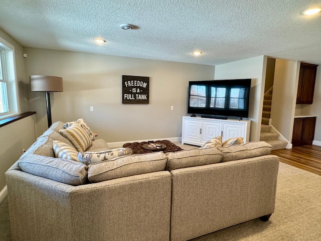 living area with a textured ceiling, stairs, baseboards, recessed lighting, and wood finished floors