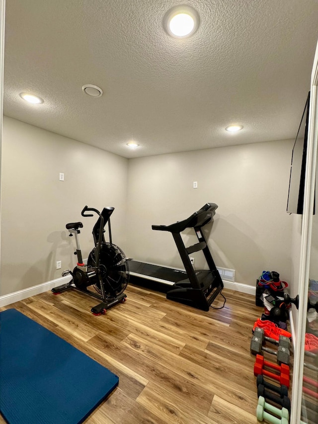 workout area with a textured ceiling, wood finished floors, recessed lighting, and baseboards