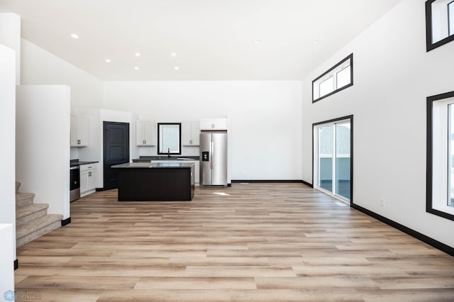 6741 67th Ave S, Horace, ND 58047 - kitchen featuring a towering ceiling, stainless steel refrigerator with ice dispenser, a center island, white cabinetry, and light wood-style flooring