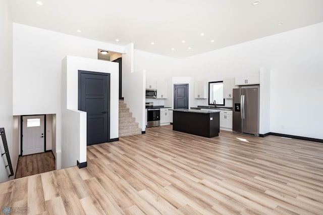 6741 67th Ave S, Horace, ND 58047 - kitchen featuring stainless steel appliances, a center island, white cabinets, light wood finished floors, and a high ceiling