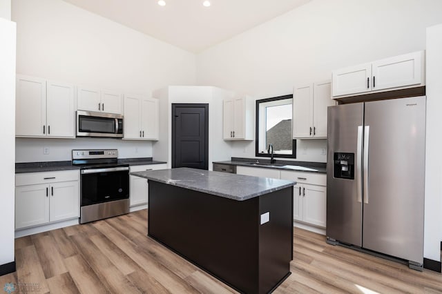 6741 67th Ave S, Horace, ND 58047 - kitchen with appliances with stainless steel finishes, a kitchen island, light wood-type flooring, a towering ceiling, and white cabinets
