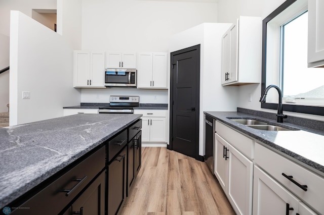 6741 67th Ave S, Horace, ND 58047 - kitchen featuring stainless steel appliances, light wood-style floors, white cabinetry, and dark stone counters