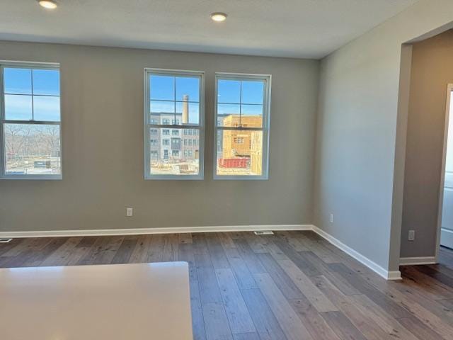empty room featuring hardwood / wood-style floors, baseboards, and recessed lighting