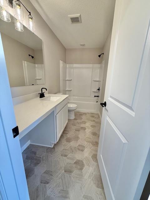 bathroom with vanity, shower / tub combination, a textured ceiling, toilet, and visible vents