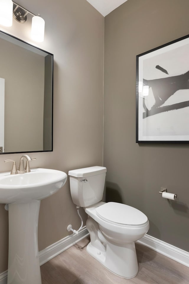 bathroom featuring toilet, wood finished floors, and baseboards