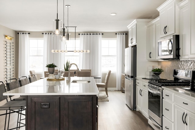kitchen featuring plenty of natural light, a sink, light countertops, a kitchen bar, and stainless steel appliances