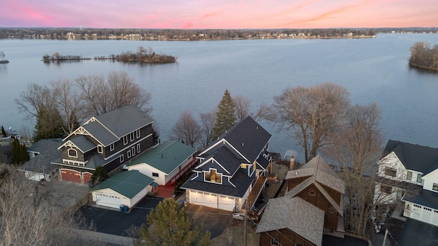 aerial view at dusk featuring a residential view and a water view