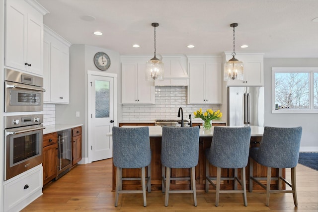 kitchen featuring stainless steel appliances, light wood-style floors, tasteful backsplash, and wine cooler