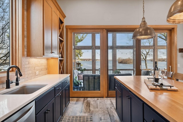 kitchen with hanging light fixtures, a sink, dishwasher, butcher block countertops, and a water view