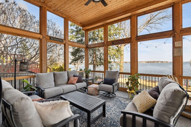 sunroom with an outdoor living space, a water view, a ceiling fan, and a towering ceiling