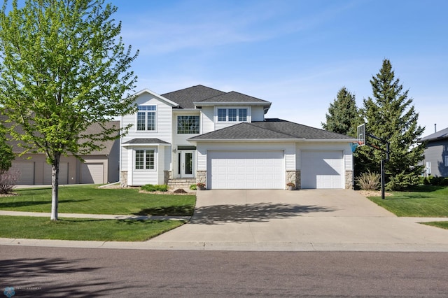 traditional-style home with stone siding, an attached garage, a front lawn, and concrete driveway