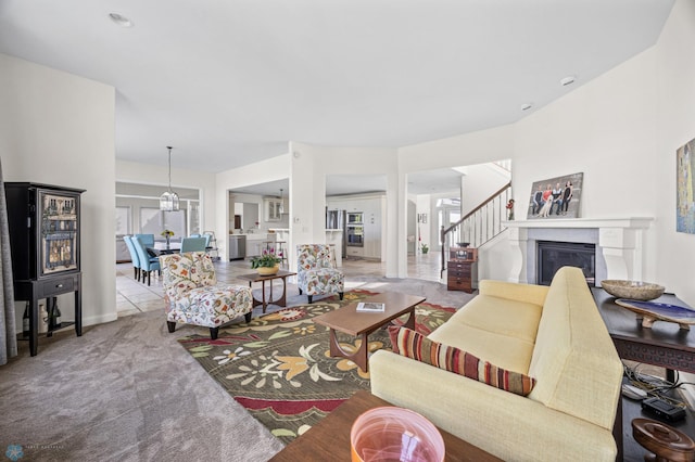 carpeted living area featuring stairs and a glass covered fireplace