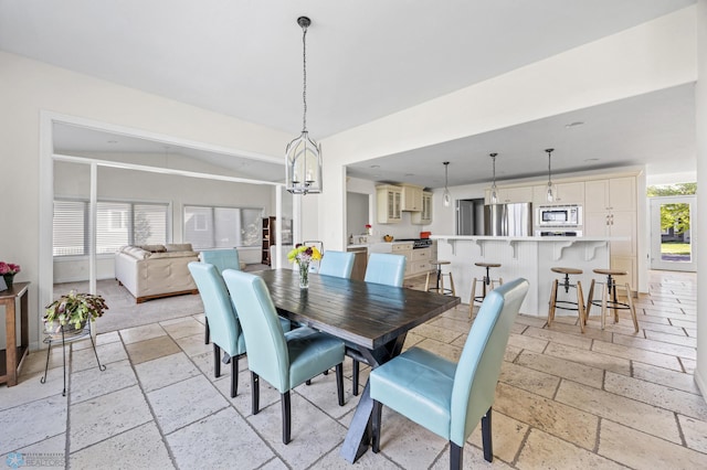 dining area featuring stone tile flooring and a chandelier