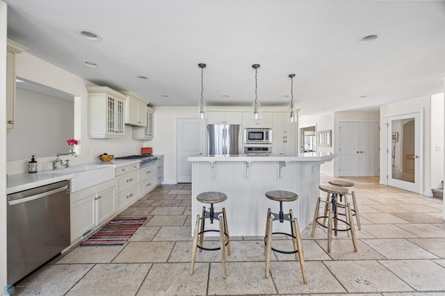 kitchen with appliances with stainless steel finishes, stone tile flooring, a breakfast bar area, light countertops, and recessed lighting