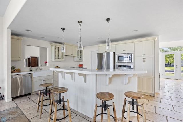 kitchen with appliances with stainless steel finishes, light countertops, a breakfast bar, glass insert cabinets, and stone tile floors