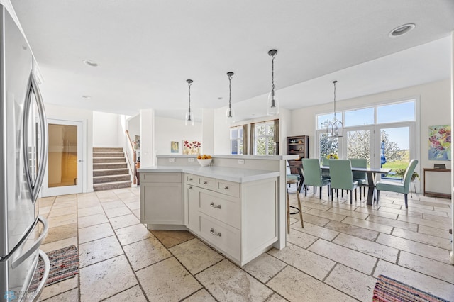 kitchen featuring freestanding refrigerator, stone tile floors, light countertops, decorative light fixtures, and recessed lighting