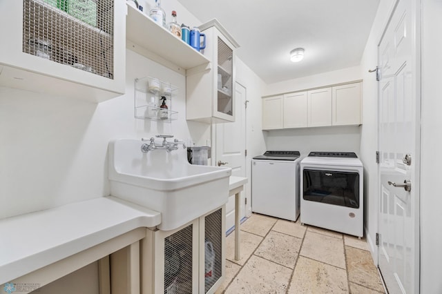 washroom featuring independent washer and dryer, stone tile flooring, and cabinet space