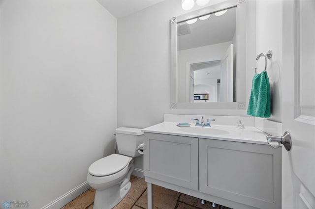 bathroom with baseboards, toilet, and vanity