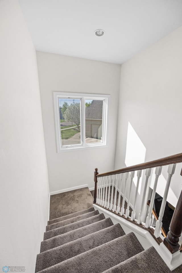 stairway featuring carpet flooring and baseboards