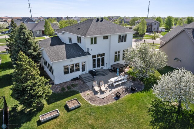 back of property featuring a residential view, a patio area, a lawn, and roof with shingles