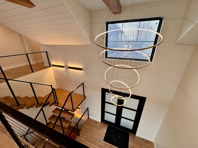 stairway with baseboards, beam ceiling, wood finished floors, and visible vents