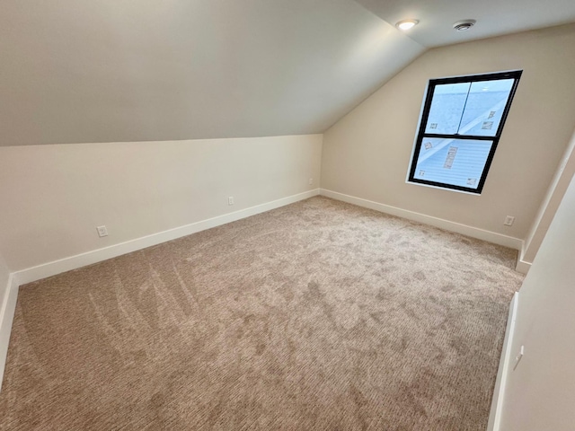 additional living space featuring baseboards, carpet, and vaulted ceiling