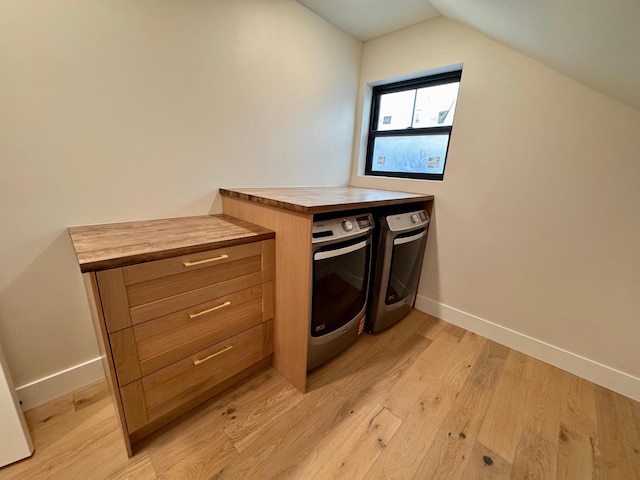 laundry room with baseboards, washer and clothes dryer, laundry area, and light wood-type flooring