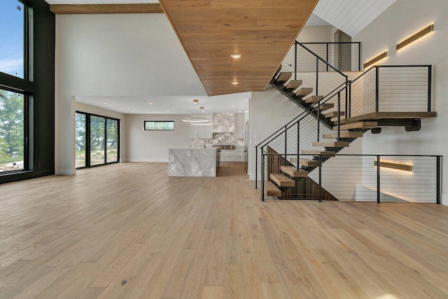 11694 Indian Beach Rd, Spicer, MN 56288 - unfurnished living room featuring a high ceiling, light wood-style flooring, stairs, recessed lighting, and wooden ceiling